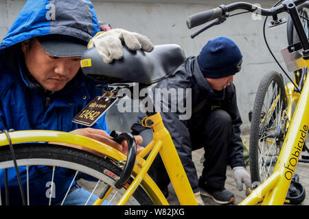 Les réparations d'un travailleur le verrou d'une location de vélos en libre-service chinois ofo à un poste de maintenance à Shanghai, Chine, 21 février 2017. Ville principale Banque D'Images