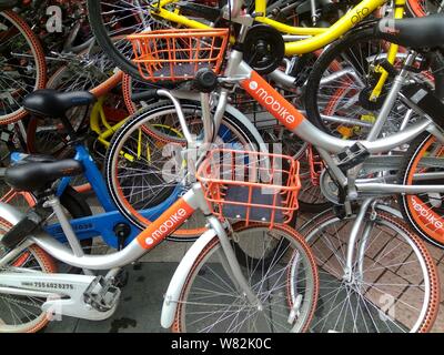 --FILE--endommagée de vélos vélo-partage des services chinois Mobike (orange), ofo (jaune) et Xiaoming Danche, ou Xiaoming Vélo (bleu) sont empilés près de Banque D'Images