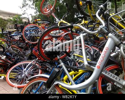 --FILE--endommagée de vélos vélo-partage des services chinois Mobike (orange), ofo (jaune) et Xiaoming Danche, ou Xiaoming Vélo (bleu) sont empilés près de Banque D'Images