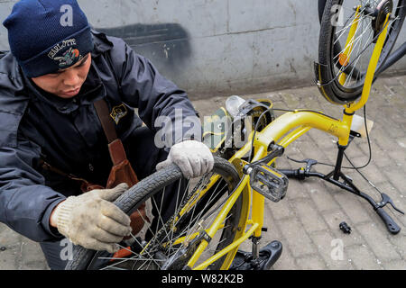 Un travailleur répare le pneu d'une location de vélos en libre-service chinois ofo à un poste de maintenance à Shanghai, Chine, 21 février 2017. Ville principale Banque D'Images