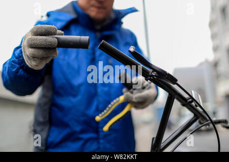 Un travailleur chinois répare le guidon d'une location de vélos en libre-service chinois ofo à un poste de maintenance à Shanghai, Chine, 21 février 2017. Banque D'Images