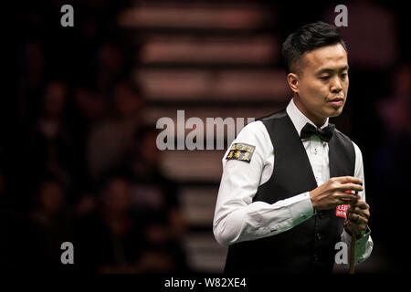 Marco Fu de Hong Kong les craies son cue qu'il estime un tir de Mark Allen de l'Irlande du Nord pendant le match quart de leurs 2017 Dafabet Mast Banque D'Images