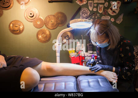 Artiste de tatouage chinois Li encres Jiaxuan la cheville d'un client dans son studio de tatouage à Changchun city, Jilin province du nord-est de la Chine, 18 novembre 20 Banque D'Images
