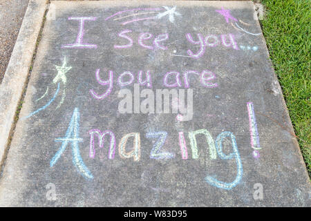 Les mots "je vous vois, vous êtes incroyable' écrit avec craies de trottoir sur fond des chaussées de béton gris Banque D'Images