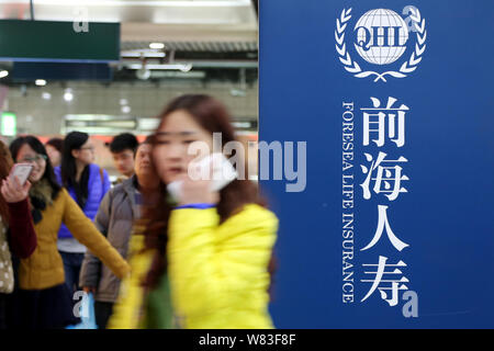 --FILE--passagers à pied passé une publicité d'Foresea l'assurance-vie (LHQ) à une station de métro à Shanghai, Chine, le 7 décembre 2014. China's insura Banque D'Images