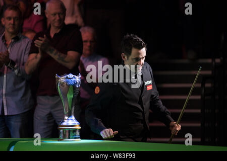 Ronnie O'Sullivan, de l'Angleterre passe devant le champion trophy dans le dernier match face à sa compatriote Mark Selby au cours de l'Championnat du Royaume-Uni en 2016 Betway Banque D'Images