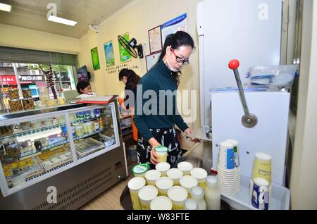 Huang Nana, l'épouse de l'éleveur chinois Zeng Bo, titulaire d'un doctorat en nutrition animale de l'Académie chinoise des sciences, l'étanchéité de la bouteille de lait en t Banque D'Images