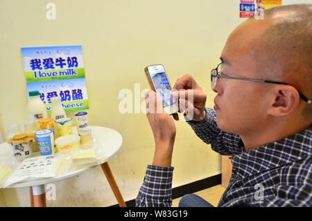 Éleveur de chinois Zeng Bo, titulaire d'un doctorat en nutrition animale de l'Académie Chinoise des Sciences, utilise son smartphone pour prendre des photos de ses produits laitiers pr Banque D'Images