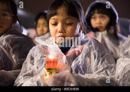 Les jeunes filles tiennent des bougies dans la pluie pendant une veillée aux chandelles pour commémorer les victimes de la Nanjing Massacre de la salle du Souvenir des victimes dans le Na Banque D'Images