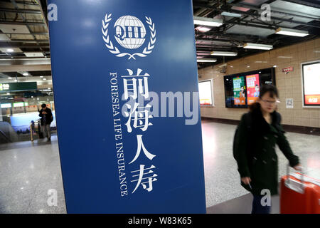 --FILE--passagers à pied passé une publicité d'Foresea l'assurance-vie (LHQ) à une station de métro à Shanghai, Chine, le 7 décembre 2014. China's insura Banque D'Images
