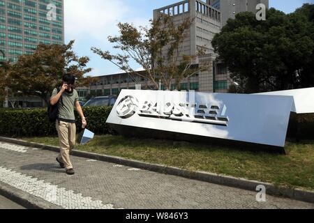 --FILE--un piéton passe devant une pancarte au siège de Baoshan Iron and Steel Co., Ltd (Baosteel) à Shanghai, Chine, le 26 septembre 2015. Banque D'Images