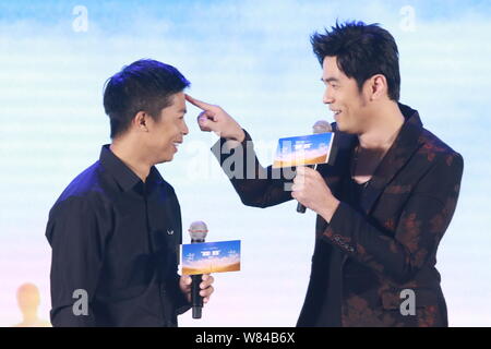 La chanteuse taïwanaise, Jay Chou droit, interagit avec un invité à une conférence de presse pour son film '10 000 milles, à Beijing, Chine, 21 octobre 2016. Banque D'Images