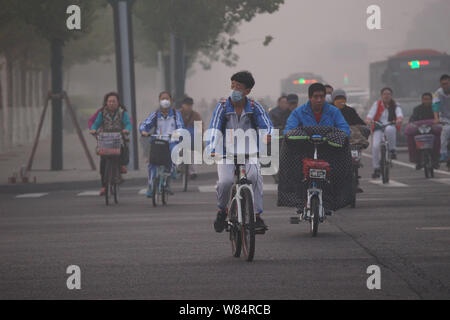 Les cyclistes chinois, dont certains portent des masques protecteurs contre la pollution atmosphérique, sur la route de lourdes le smog dans Tianjin, Chine, 19 octobre 2016. Beijing env Banque D'Images