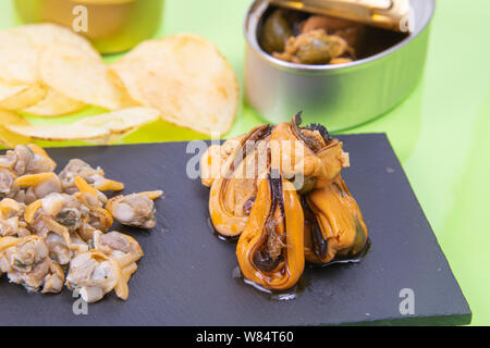 Vue de dessus les moules marinées accompagné de coques savoureux servis sur une plaque en pierre rustique noir avec frites et d'une décoration en étain la photo Banque D'Images