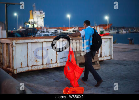 Malaga, Espagne. 07Th Aug 2019. Un membre de la Garde côtière canadienne et européenne des frontières (Frontex) est l'Agence vu porter un gilet et un flotteur de migrants à un récipient après leur arrivée au Port de Malaga. Service de Sauvetage Maritime de l'Espagne a sauvé un total de 73 migrants à bord d'un canot traversant la mer d'Alboran et les apporta à Malaga port, où ils étaient assistés par la Croix Rouge Espagnole. Autour de 163 migrants ont été secourus au cours des dernières heures. Credit : SOPA/Alamy Images Limited Live News Banque D'Images
