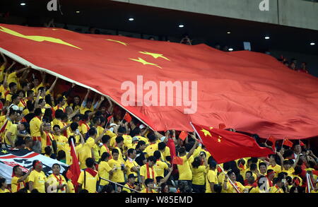 Les fans de football chinois passent sur un drapeau national géant pour montrer leur soutien à l'équipe de la Chine au cours d'un groupe d'un match de football entre la Chine et la Corée du Sud de Banque D'Images