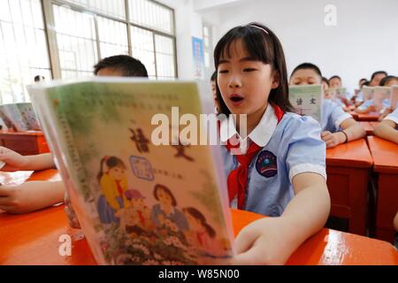 Les jeunes étudiants chinois lu à voix haute leurs manuels scolaires chinois pendant une leçon en classe dans une école primaire le premier jour du nouveau semestre en Banque D'Images