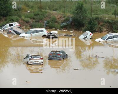 Les voitures privées sont submergés dans l'eau après avoir été lavés par les inondations causées par un orage dans une fosse de l'aire de stationnement dans un quartier résidentiel Banque D'Images