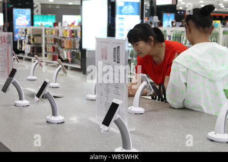 --FILE--un client chinois essaie de smartphones iPhone dans un Apple Store dans la ville de Xuchang, province du Henan en Chine centrale, 7 août 2016. Smartphone Blackberry Banque D'Images