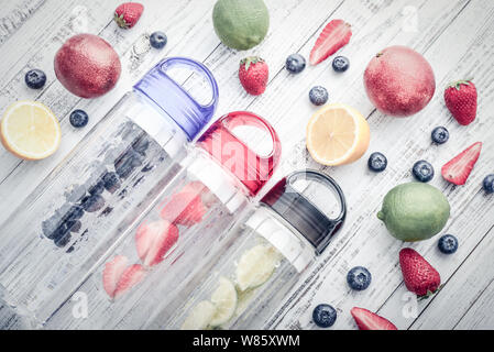 L'eau en bouteille detox infusée avec fruits frais et de baies sur fond de bois, vue du dessus Banque D'Images