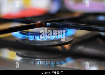 La combustion de gaz naturel sur la cuisine cuisinière à gaz dans l'obscurité. Bord en acier avec un brûleur gaz sur un fond noir, des prises de vue rapprochées Banque D'Images
