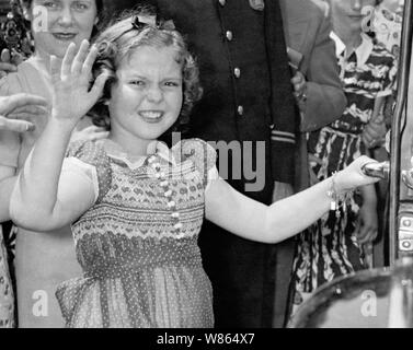 Vintage photo d'enfant américain film star Shirley Temple (1928 - 2014). La photo a été prise le 24 juin 1938 que la jeune actrice fait signe aux spectateurs après avoir quitté la Maison Blanche à la suite d'une réunion avec le président américain Franklin D. Roosevelt. Au cours de leur conversation, elle a dit au président comment elle avait perdu une dent la nuit avant qu'il ne tombe que lorsqu'elle a mangé un sandwich. Banque D'Images