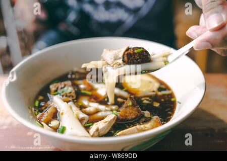 Close up Guay jub, sauce soupe de nouilles thai street food on table en bois avec la main et la fourchette Banque D'Images