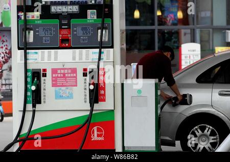 --FILE--un pilote chinois ravitaille sa voiture dans une station de Sinopec à Nanjing, Jiangsu province de Chine orientale, le 25 mai 2016. Des filiales de Ch Banque D'Images