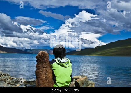 L'homme chinois Xiao Yu de Xing'an, ville de Guilin, Chine du Sud, région autonome Zhuang du Guangxi, et son chien regarde le Lac Yamdrok comme ils Banque D'Images