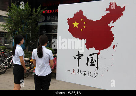 Les piétons regardez une photo montrant du territoire chinois dans une rue de la ville de Weifang, province de Shandong, Chine orientale, le 14 juillet 2016. La Chine a promis de ta Banque D'Images