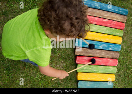 L'apprentissage de la musique par un enfant. Jeune garçon à jouer du xylophone dans un jardin Banque D'Images