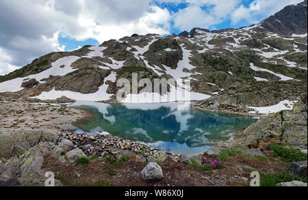 Magnifique lac de haute montagne dans les Alpes françaises avec de l'eau turquoise et couverte de neige à certains endroits Banque D'Images