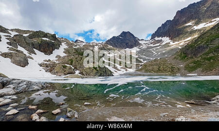 Magnifique lac de haute montagne dans les Alpes françaises avec de l'eau turquoise et couverte de neige à certains endroits. Panorama du lac Blanc Banque D'Images