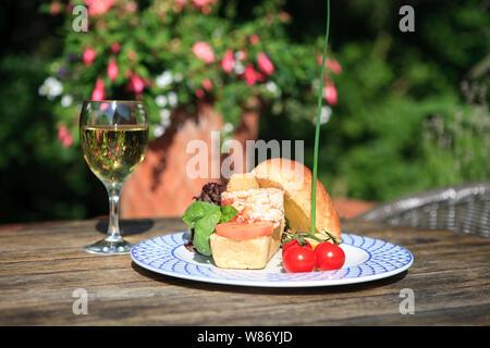 Un sandwich fait avec du crabe frais servis avec salade de Guernesey en plein air, dans le soleil de l'été avec un verre de vin blanc. Banque D'Images