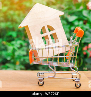 Maison en bois dans un chariot de supermarché. Investissement immobilier et financier hypothécaire concept. L'achat, la location et la vente d'appartements. L'immobilier. Les moyens Banque D'Images