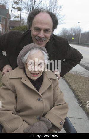 90 ans femme avec son fils de 57 ans dehors pour un peu d'air en hiver. Banque D'Images