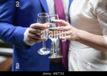 Homme et une femme tenant des flûtes à champagne et de grillage, le concept de couples célébrant un mariage, toast, amis ou collègues night out Banque D'Images