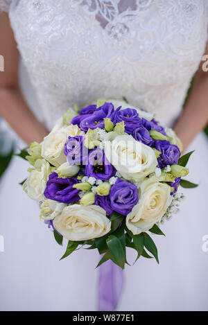 Les femmes de race blanche dans la belle lacy robe blanche tenant un grand bouquet rond avec roses et mauves ivoire lors d'une cérémonie de mariage Banque D'Images