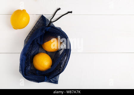 Un sac filet réutilisable pour faire ses courses rempli de citron sur fond blanc. Concept d'arrêter l'utilisation de plastique à usage unique,zéro déchets et l'éco- frie Banque D'Images