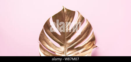 Golden palm feuilles monstera tropical peint à la mode sur fond de couleur rose corail vivant. L'espace vide, place pour le texte, copier, lettrage. Beauté, brillant Banque D'Images