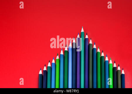 Concept d'équipe. groupe de crayon de couleur sur fond rouge Banque D'Images