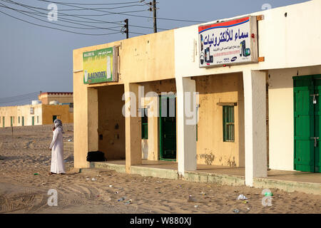 Homme debout en bordure du désert avec shbuilding et blanchisserie vente et réparer l'électronique et les appareils mobiles, téléphones dans un village, Sultanat d'Oman Banque D'Images