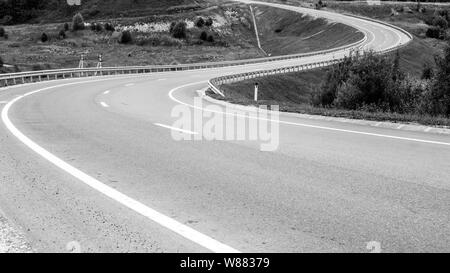 Route sinueuse passe dans la distance. Image en noir et blanc. Concept de voyage Banque D'Images
