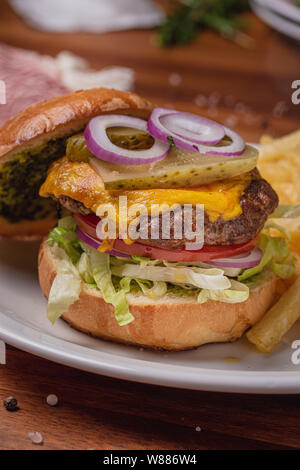 Hamburger et des frites servi sur assiette de porcelaine blanche sur fond de table en bois Banque D'Images