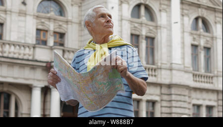 Senior male tourist explorer la ville avec une carte dans les mains et à l'itinéraire lors d'un voyage à Lviv, Ukraine. T-shirt pull et dans son cou. Locations de concept Banque D'Images