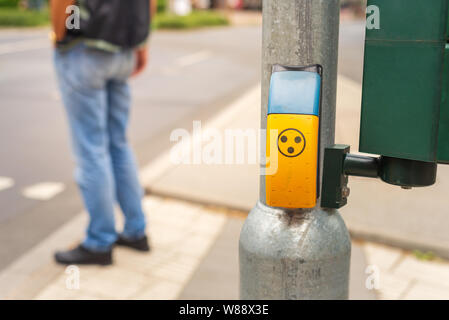 Passage pour piétons ou signe jaune bouton-poussoir de concordance sur métal à côté de passage pour piétons dans la rue en Allemagne. Banque D'Images