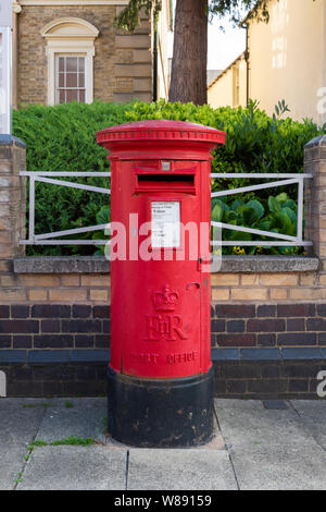 Market Harborough, Leicestershire, UK : bureau de poste rouge fonte Elizabeth II pilier Post Office box sur un trottoir avec un muret et rambarde derrière. Banque D'Images