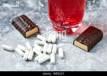 Capsules d'arginine, High Protein bar et BCAA boisson. Bodybuilding suppléments alimentaires sur fond noir en lumineux. Close up. Copier l'espace. Banque D'Images