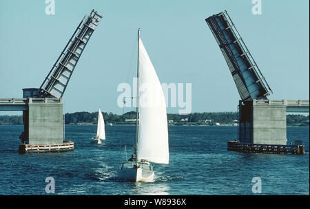 Un pont-levis à double battant s'ouvre pour permettre deux voiliers à poursuivre leur passage sur l'Indian River, près de Saint Lucie sur la côte est de la Floride, aux États-Unis. Techniquement connu comme un pont à bascule (du mot français pour seesaw), il a deux longueurs d'acier identiques qui s'étendent sur la voie d'eau et ouvert dans l'air à l'aide de contrepoids dans l'appui concret des jetées de part et d'autre. La conception de ce pont est semblable à ceux qui s'est étendue sur les douves des châteaux médiévaux, sauf qu'ils étaient des types de feuilles qui s'est ouvert dans l'air seulement d'un côté. Banque D'Images