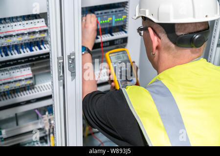 Ingénieur électrique effectue une mesure dans une armoire de commande Banque D'Images